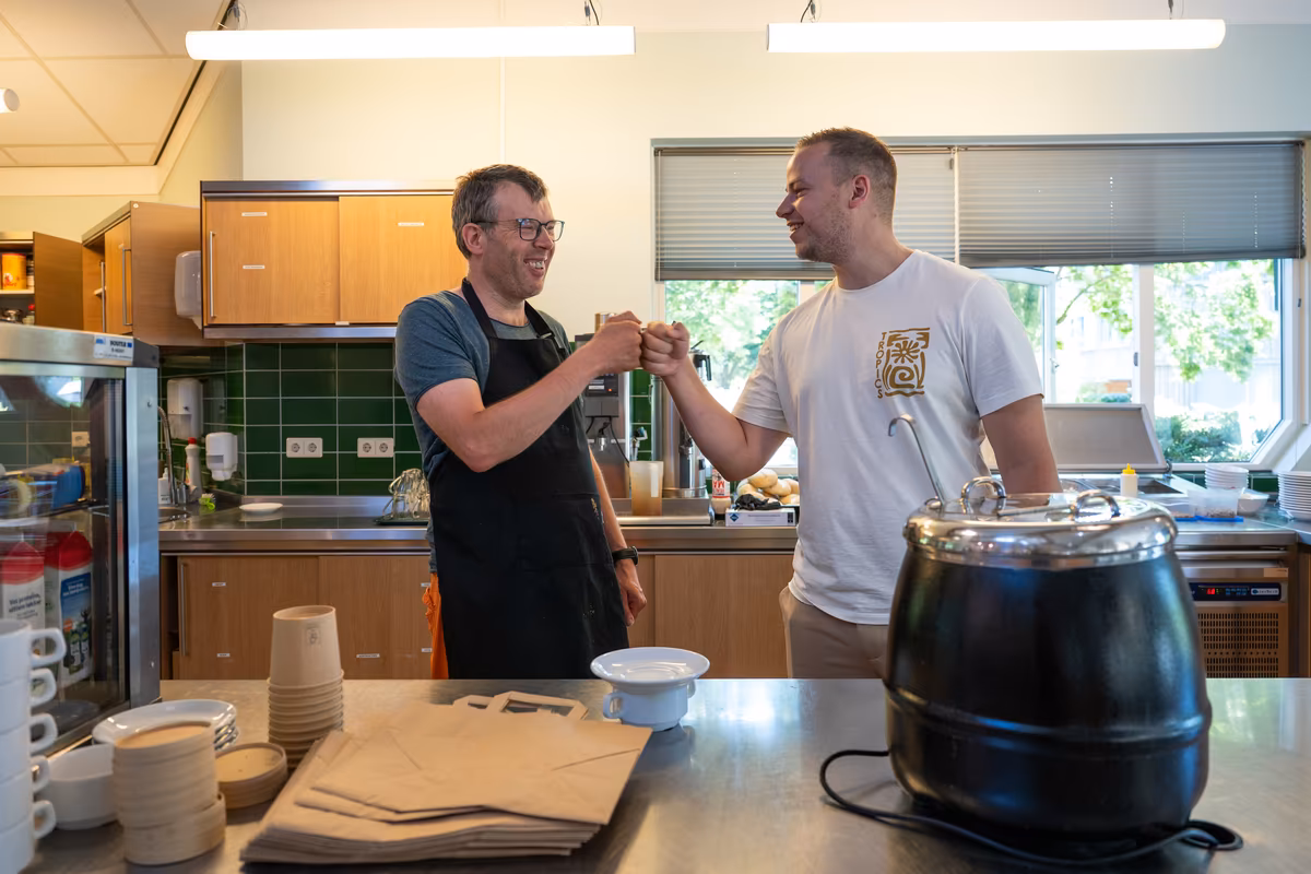 Samenwerken in het restaurant Cliënt en begeleider geven elkaar een boks in de keuken van De Waterjuffers